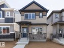 Two-story residence featuring a covered front porch, stone and siding exterior, front entry door with transom window, and a concrete walkway - 3611 Triomphe Boulevard, Beaumont, AB 