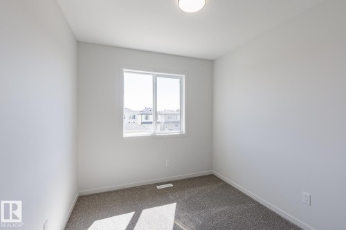 Carpeted room with a single window and flush mount lighting - 3611 Triomphe Boulevard, Beaumont, AB 