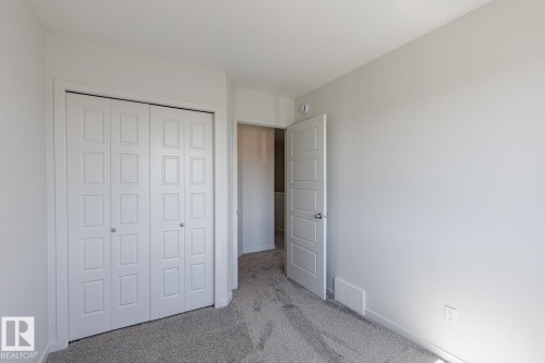 Neutral-toned walls, grey carpet, interior door with paneling, and a bi-fold closet - 3611 Triomphe Boulevard, Beaumont, AB 