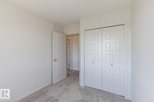 Plush carpet flooring, neutral paint palette, paneled interior door, and bi-fold closet doors - 3611 Triomphe Boulevard, Beaumont, AB 