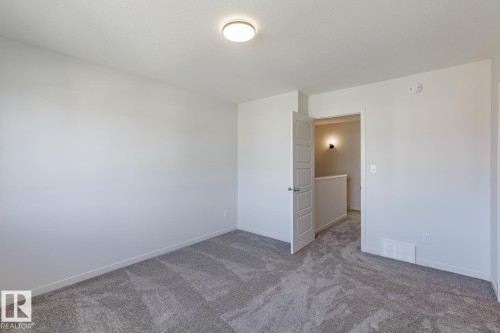 Neutral wall colors, textured carpet flooring, and a flush mount ceiling light - 3611 Triomphe Boulevard, Beaumont, AB 