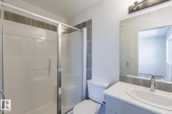 Shower with sliding glass enclosure, white integrated vanity with undermount sink, chrome faucet, and vanity light fixture - 