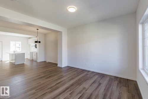 Open-concept layout with wood-finish flooring, recessed lighting, and a modern kitchen island with an undermount sink - 3611 Triomphe Boulevard, Beaumont, AB 