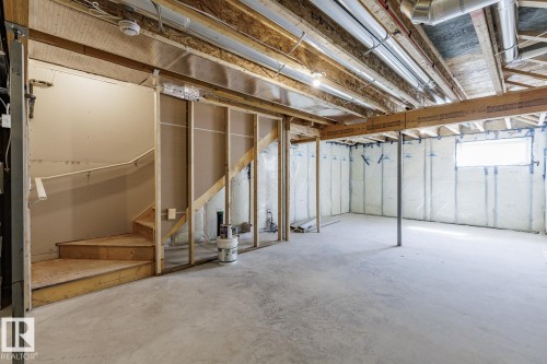 Unfinished lower level with wood framing, exposed joists, concrete flooring, and an unfinished wood staircase - 3611 Triomphe Boulevard, Beaumont, AB 