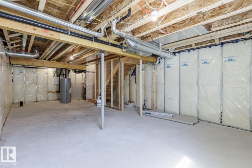 Unfinished lower level with exposed ceiling joists, concrete flooring, and partial wall insulation - 3611 Triomphe Boulevard, Beaumont, AB 