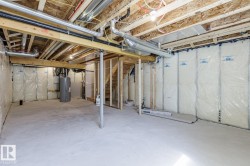 Unfinished lower level with exposed ceiling joists, concrete flooring, and partial wall insulation - 
