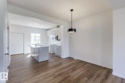 Wood-finish flooring, white walls, and a modern pendant light - 