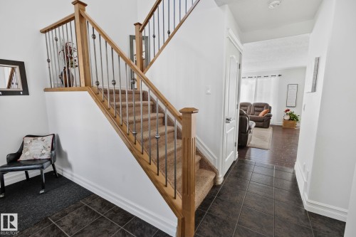 Carpeted staircase with wood-finish handrails and metal balusters - 1115 61 Street Sw, Edmonton, AB 