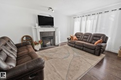 Living room with a fireplace featuring a white mantel and tile surround, recessed lighting, and dark wood-finish flooring - 