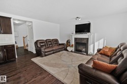 Dark wood-finish flooring, white walls, built-in fireplace with tile surround, white mantel, dark wood cabinetry with light countertop, and light-colored subway tile backsplash - 