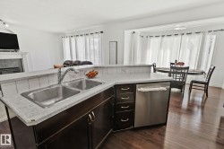 Kitchen island with dual stainless steel sink, integrated dishwasher, and dark wood cabinetry - 