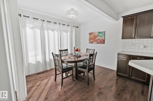 Hardwood-finish flooring, white walls, dark wood-finish cabinetry, light-colored countertops, and a white subway tile backsplash - 1115 61 Street Sw, Edmonton, AB 