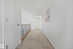 Neutral-toned wall-to-wall carpeting, white interior doors with contemporary hardware, and a wood and wrought iron staircase railing - 