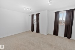 Spacious room featuring neutral carpet, two windows with dark drapery, and track lighting fixtures - 