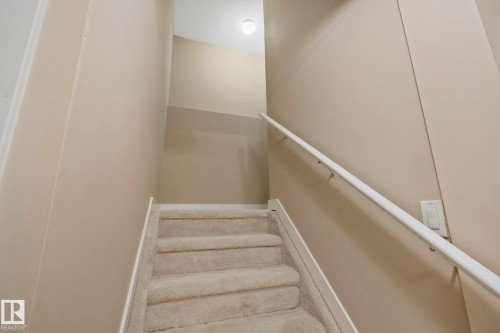 Carpeted staircase with a white handrail and neutral wall tones - 1115 61 Street Sw, Edmonton, AB 