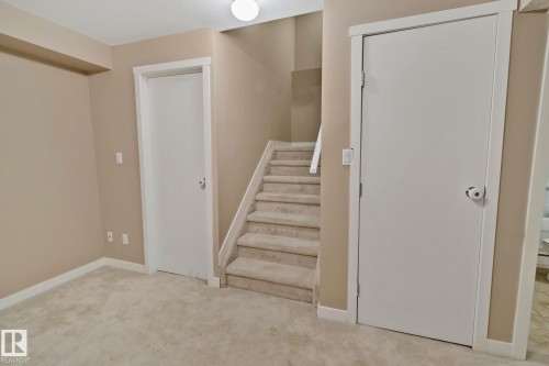 Plush carpet flooring, neutral wall tones, white trim, and staircase with carpeted treads - 1115 61 Street Sw, Edmonton, AB 