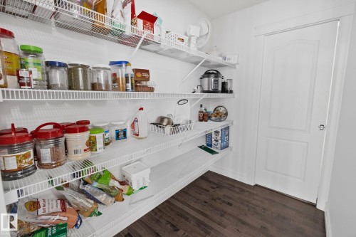 Spacious pantry with multiple wire shelving units, dark wood-finish flooring, and a white paneled door - 1115 61 Street Sw, Edmonton, AB 