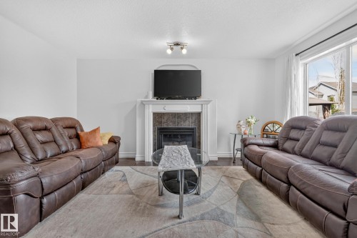 Living area featuring a fireplace with a white mantel, tile surround, and an integrated television mount - 1115 61 Street Sw, Edmonton, AB 