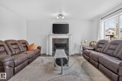 Living area featuring a fireplace with a white mantel, tile surround, and an integrated television mount - 