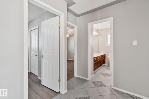 Hallway featuring light gray wall paint, white trim, and a combination of wood-finish flooring and patterned tile - 14724 73 Street Nw, Edmonton, AB 
