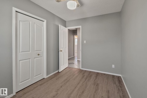 Wood-finish flooring, light gray wall paint, white trim, and a ceiling fan with integrated lighting - 14724 73 Street Nw, Edmonton, AB 