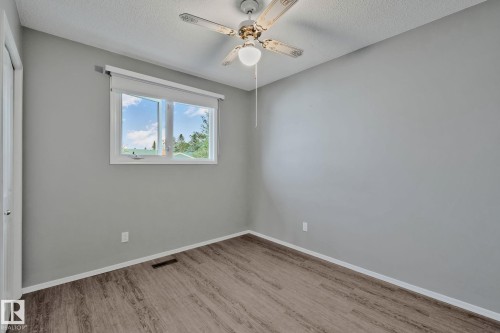 Wood-finish flooring, light gray wall tones, ceiling fan with integrated lighting, and a double-pane window - 14724 73 Street Nw, Edmonton, AB 