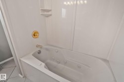 Jetted soaking tub with bright white surrounds and gold-finish fixtures - 