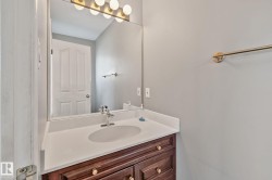 Vanity with a white countertop and integrated sink, chrome faucet, and a wood-finish cabinet with gold-tone hardware - 