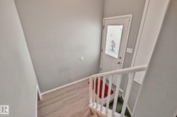 Entry door with decorative glass inlay, wood-finish flooring, and a white painted handrail - 