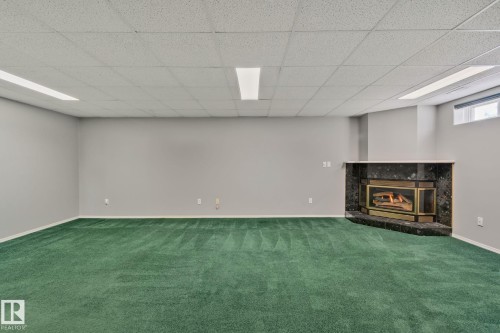 Corner fireplace featuring a dark stone surround and hearth - 14724 73 Street Nw, Edmonton, AB 