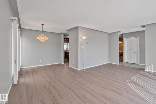 Wood-finish flooring throughout, with neutral wall paint, and a crystal chandelier - 14724 73 Street Nw, Edmonton, AB 