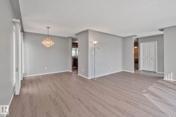 Wood-finish flooring throughout, with neutral wall paint, and a crystal chandelier - 