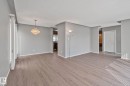 Wood-finish flooring throughout, with neutral wall paint, and a crystal chandelier - 14724 73 Street Nw, Edmonton, AB 