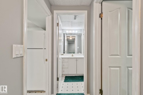 Bathroom featuring a white vanity with built-in storage, a white countertop, and a wall-mounted mirror with overhead lighting - 14724 73 Street Nw, Edmonton, AB 