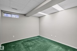 Room featuring green carpeting, light gray walls, a drop ceiling with integrated lighting, and a horizontal window - 