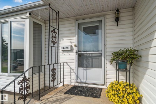 Front entry featuring white siding, decorative black wrought iron railing, and a bay window - 14724 73 Street Nw, Edmonton, AB 