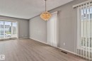 Neutral gray wall paint, wood-finish flooring, two large windows with vertical blinds, and a decorative chandelier - 14724 73 Street Nw, Edmonton, AB 