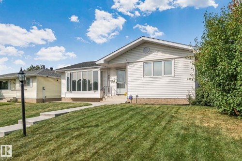 White siding exterior with a front lawn, mature shrubs, and a concrete walkway - 14724 73 Street Nw, Edmonton, AB 