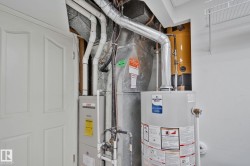 Utility area with a water heater, furnace, and exposed ductwork - 