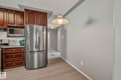 Kitchen featuring rich wood cabinetry, stainless steel refrigerator, built-in microwave, a gas range, and wood-finish flooring - 