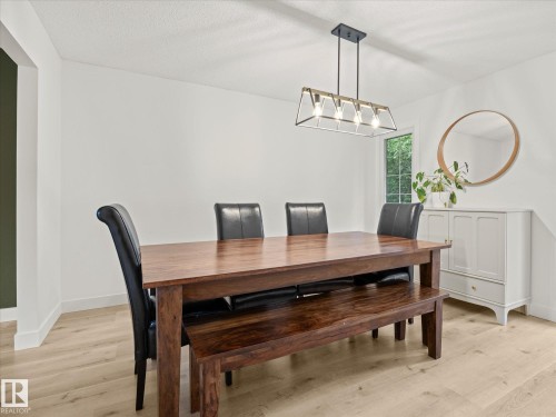 Bright room featuring light wood-finish flooring, white walls, and a modern linear chandelier with exposed bulbs - 4 Lovatt Place, St. Albert, AB - Indoor Photo Showing Dining Room