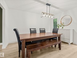 Bright room featuring light wood-finish flooring, white walls, and a modern linear chandelier with exposed bulbs - 