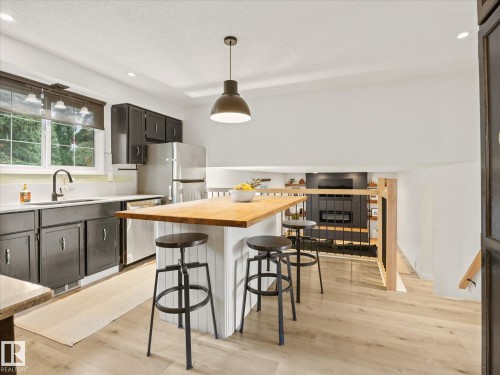 Kitchen featuring light wood-finish flooring, dark cabinetry, and light-toned countertops - 4 Lovatt Place, St. Albert, AB - Indoor Photo Showing Kitchen