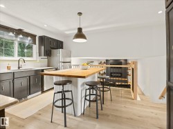 Kitchen featuring light wood-finish flooring, dark cabinetry, and light-toned countertops - 
