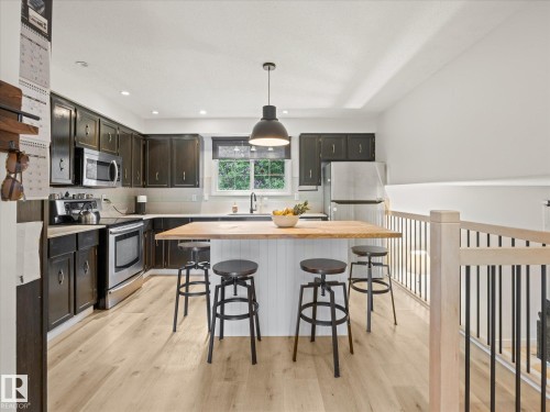 Kitchen featuring dark cabinetry, stainless steel appliances, and wood-finish flooring - 4 Lovatt Place, St. Albert, AB - Indoor Photo Showing Kitchen With Upgraded Kitchen