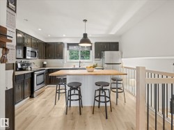 Kitchen featuring dark cabinetry, stainless steel appliances, and wood-finish flooring - 