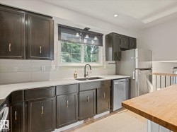 Kitchen featuring dark wood cabinetry with gold-toned hardware, light-toned countertops, subway tile backsplash, and a stainless steel refrigerator - 