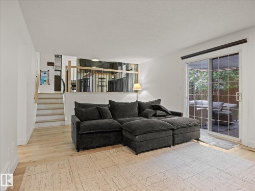 Bright living area featuring light wood-finish flooring, a neutral area rug, and a sliding glass patio door - 4 Lovatt Place, St. Albert, AB - Indoor Photo Showing Living Room