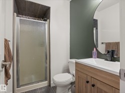 Bathroom featuring a walk-in shower with a frosted glass enclosure and dark tile surround - 