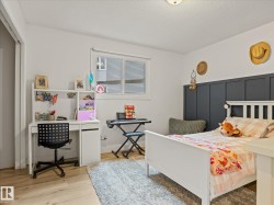 Bedroom featuring wood-finish flooring, white walls, and a recessed window - 